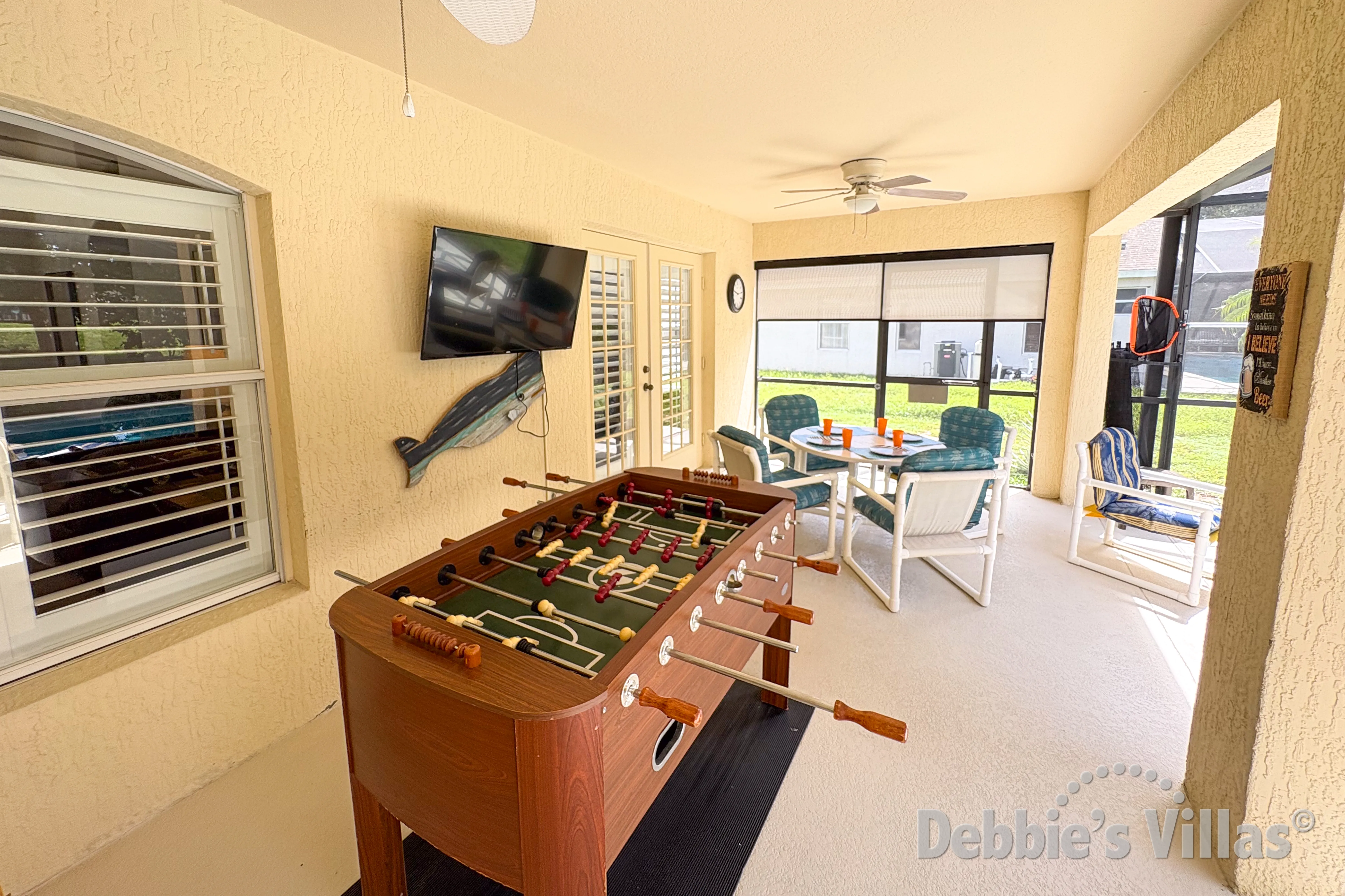 Covered seating area with a poolside TV and table football